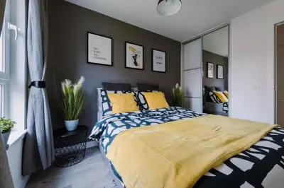 a bedroom with a king sized bed with yellow pillows at ComfySleep Apartments in Glasgow