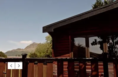 a log cabin with mountains in the background at Caol Gleann Lodge in Rowardennan