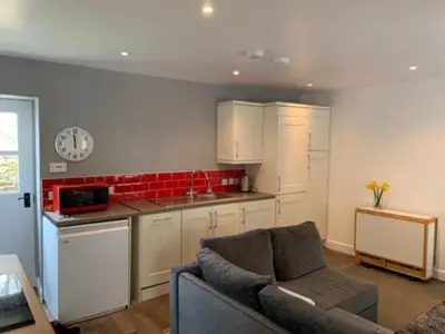 a living room with a couch and a kitchen at Boggle Dyke Cottage in Thornhill