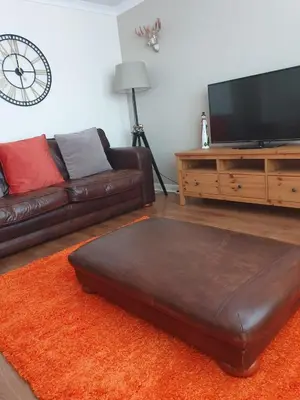 a living room with a leather couch and a flat screen tv at Largs stay With Private parking in Largs