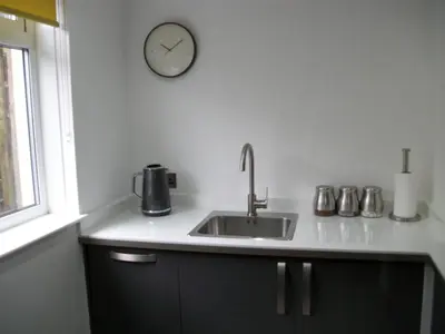 a kitchen with a sink and a clock on the wall at Westpark Apartment in East Kilbride