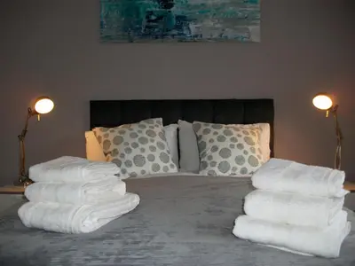 a pile of towels sitting on top of a bed at Westpark Apartment in East Kilbride
