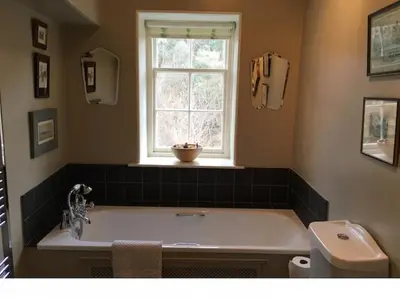 a bathroom with a bath tub and a window at Neidpath Castle Cottage in Peebles
