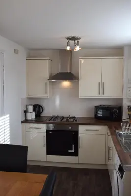 a kitchen with white cabinets and a stove top oven at Kelpies Serviced Apartments-McKay in Falkirk