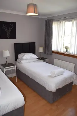 a bedroom with two beds and two windows at Kelpies Serviced Apartments-McKay in Falkirk