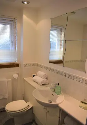a bathroom with a sink and a toilet and a mirror at Kelpies Serviced Apartments-McKay in Falkirk