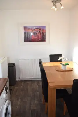 a dining room table with chairs and a picture on the wall at Kelpies Serviced Apartments-McKay in Falkirk
