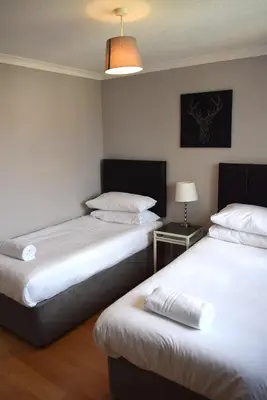 a room with two beds and a table with a lamp at Kelpies Serviced Apartments-McKay in Falkirk