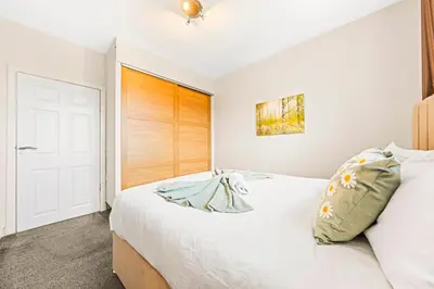 a bedroom with a white bed and a wooden door at Three Bed Holiday Home in Glasgow in Glasgow