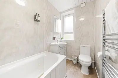 a white bathroom with a tub and a toilet and a sink at Three Bed Holiday Home in Glasgow in Glasgow