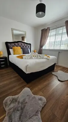 a bedroom with a large bed with a wooden floor at Silverburn new house with free parking and nice garden in Glasgow