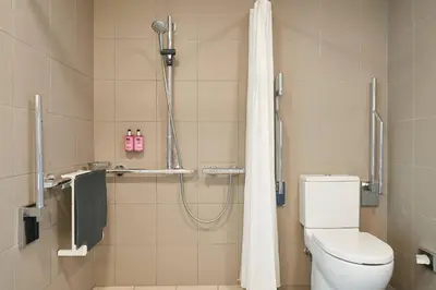 a bathroom with a shower with a toilet and a shower curtain at Moxy Edinburgh Airport in Ingliston