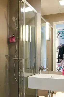 a bathroom with a shower and a sink and a mirror at Moxy Edinburgh Airport in Ingliston