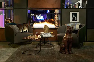 a living room with two chairs and a fireplace at Moxy Edinburgh Airport in Ingliston