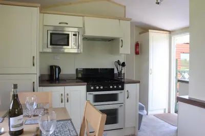 a kitchen with a stove and a microwave and a table at Ben View in Taynuilt