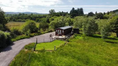 a small cabin in a field next to a road at Loch View in Taynuilt