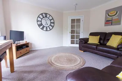 a living room with a couch and a clock on the wall at South Groathill - Lovely 2 bed with Castle View in Edinburgh