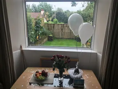 a table with balloons and a bowl of fruit and a window at A Wee Cottage In Dunfermline in Dunfermline