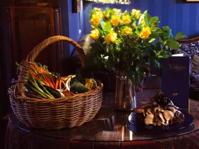 a table with a basket of vegetables and a basket of flowers at Champany Inn in Linlithgow