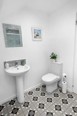 a white bathroom with a sink and a toilet at Beautiful 2BR Apartment with McCaigs Tower views in Oban