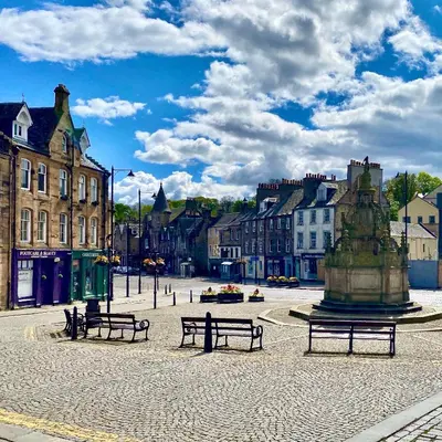 a park with benches and a fountain in a city at Central Apartment Linlithgow in Linlithgow