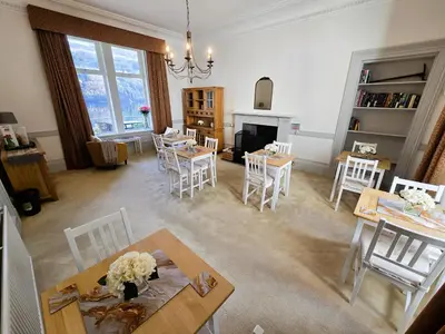 a living room with tables and chairs and a fireplace at Lochwood Guest House in Lochgoilhead