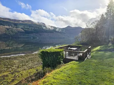 a wooden bench sitting next to a body of water at Lochwood Guest House in Lochgoilhead