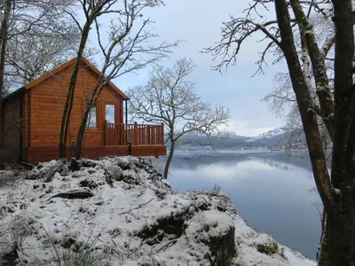 a cabin on the side of a lake in the snow at Lochwood Guest House in Lochgoilhead