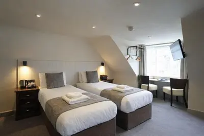 a hotel room with two beds and a desk and a table at The Whisky Vaults in Oban