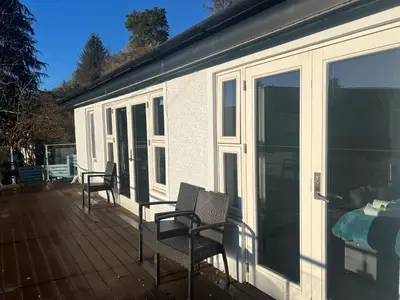 a screened in porch with two chairs on a deck at Glenisle Cottage in Lamlash