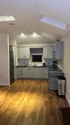 a kitchen with white cabinets and a hard wood floor at Glenisle Cottage in Lamlash