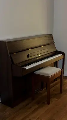 a brown piano with a stool next to it at Glenisle Cottage in Lamlash