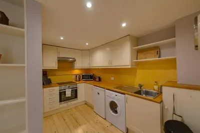 a kitchen with white cabinets and a sink and a dishwasher at JOIVY Warm & Welcoming Flat near Edinburgh Castle in Edinburgh