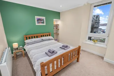 a bedroom with a large bed and a window at Central Stay on Main st- Harbour Views in Oban