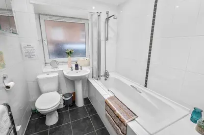 a white bathroom with a toilet and a sink at Central Stay on Main st- Harbour Views in Oban