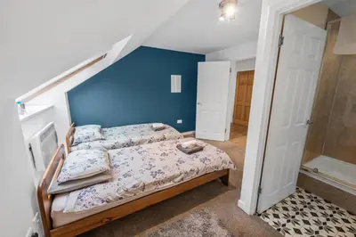 a bedroom with a bed with a blue wall at Stunning 2BR Loft Apt in Oban - Sea Views in Oban