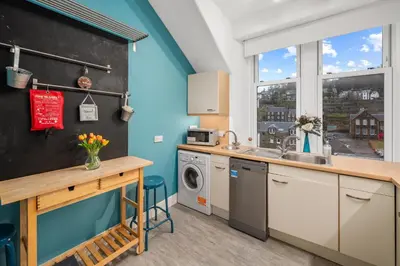 a kitchen with a sink and a washing machine at Panoramic Sea Views - Stunning 3BD Apt & Balcony in Oban