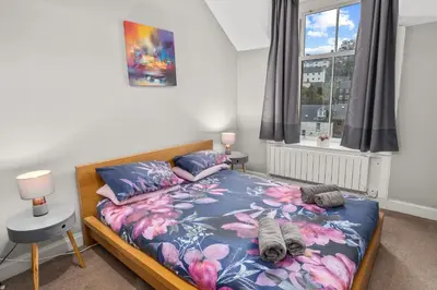 a bedroom with a bed with a blue and pink bedspread at Panoramic Sea Views - Stunning 3BD Apt & Balcony in Oban