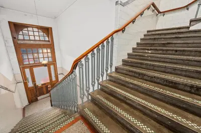 a staircase in a building with a wooden door at Panoramic Sea Views - Stunning 3BD Apt & Balcony in Oban