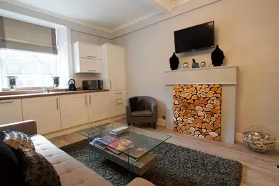 a living room with a fireplace with a tv above it at JOIVY Unique Old Town Stay under Edinburgh Castle in Edinburgh
