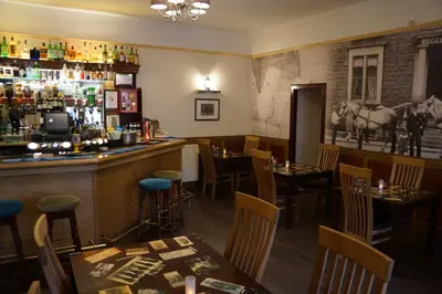 a bar in a restaurant with tables and chairs at Buccleuch Arms Hotel in Moffat