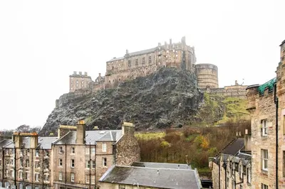 a castle on top of a hill with buildings at JOIVY Classic Apt with Castle Views in Old Town in Edinburgh