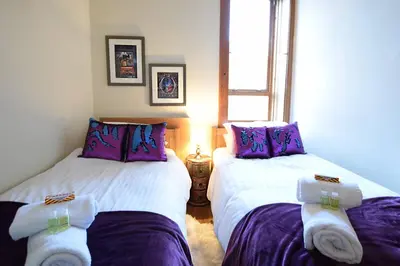 two beds in a room with purple and white sheets at JOIVY Classic Apt with Castle Views in Old Town in Edinburgh