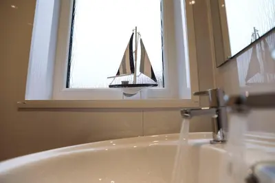 a bathroom sink with a toy boat in a window at Baron View Apartment in Paisley