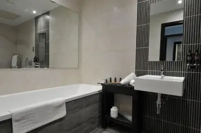 a bathroom with a tub and a sink and a mirror at The Lodge On Loch Lomond Hotel in Luss