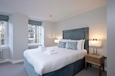 a bedroom with a large bed and two windows at Destiny Scotland New Town Apartments in Edinburgh
