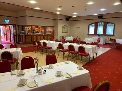 a banquet hall with white tables and red chairs at Dunmar House Hotel - Bar & Restaurant in Alloa