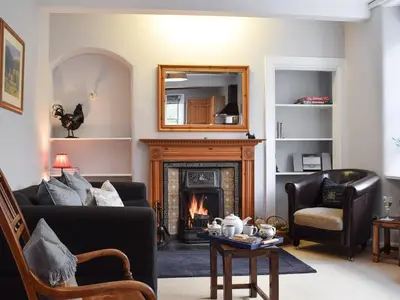 a living room with a fireplace and a mirror at Ardchoille Cottage in Fortingall