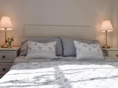 a bed with two lamps and two pillows on it at Ardchoille Cottage in Fortingall