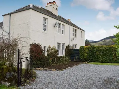 a white house with a fence in front of it at Ardchoille Cottage in Fortingall